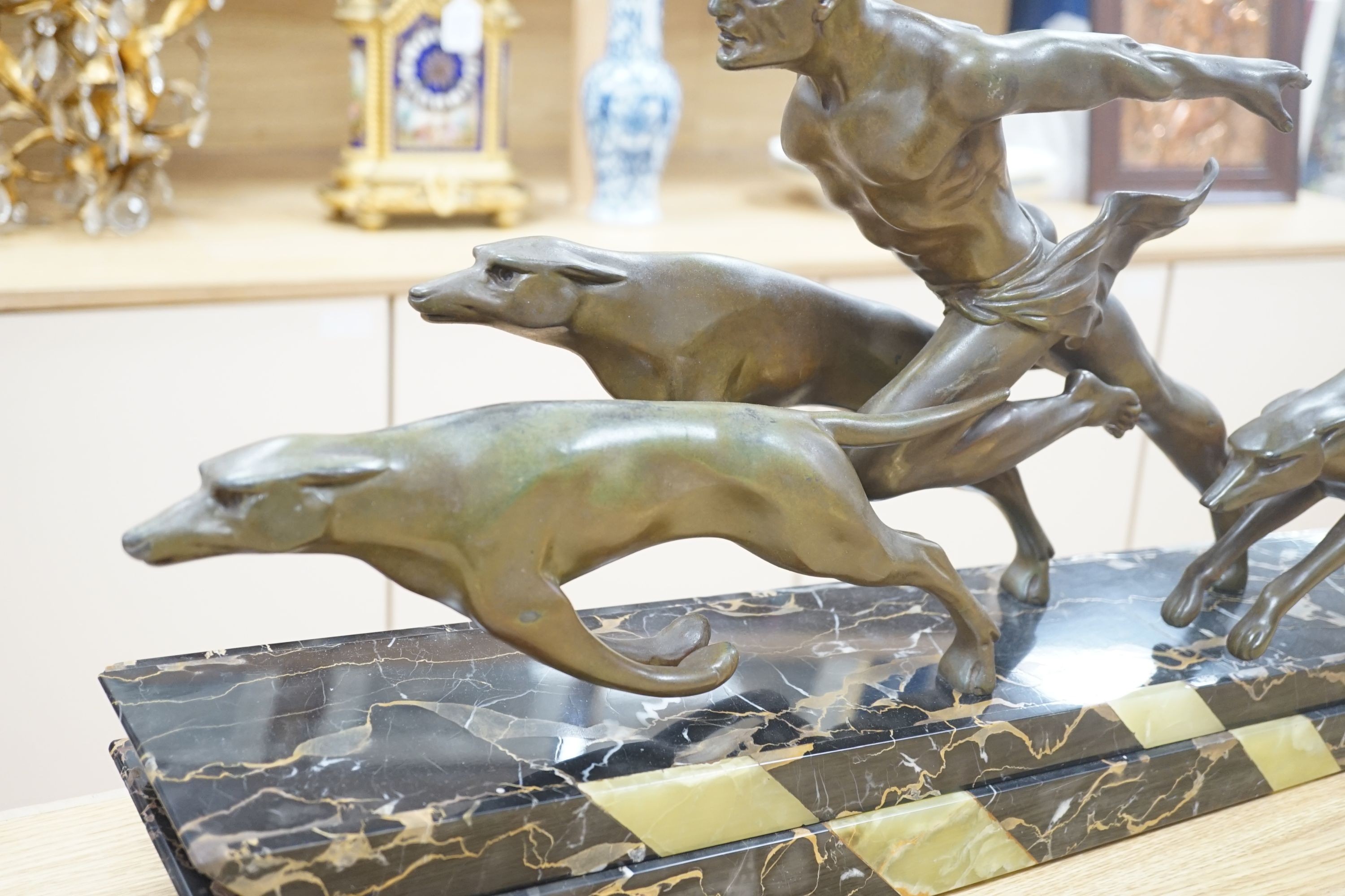 An Art Deco bronzed metal and marble running man with greyhounds, signed L Valderi, 85cm long